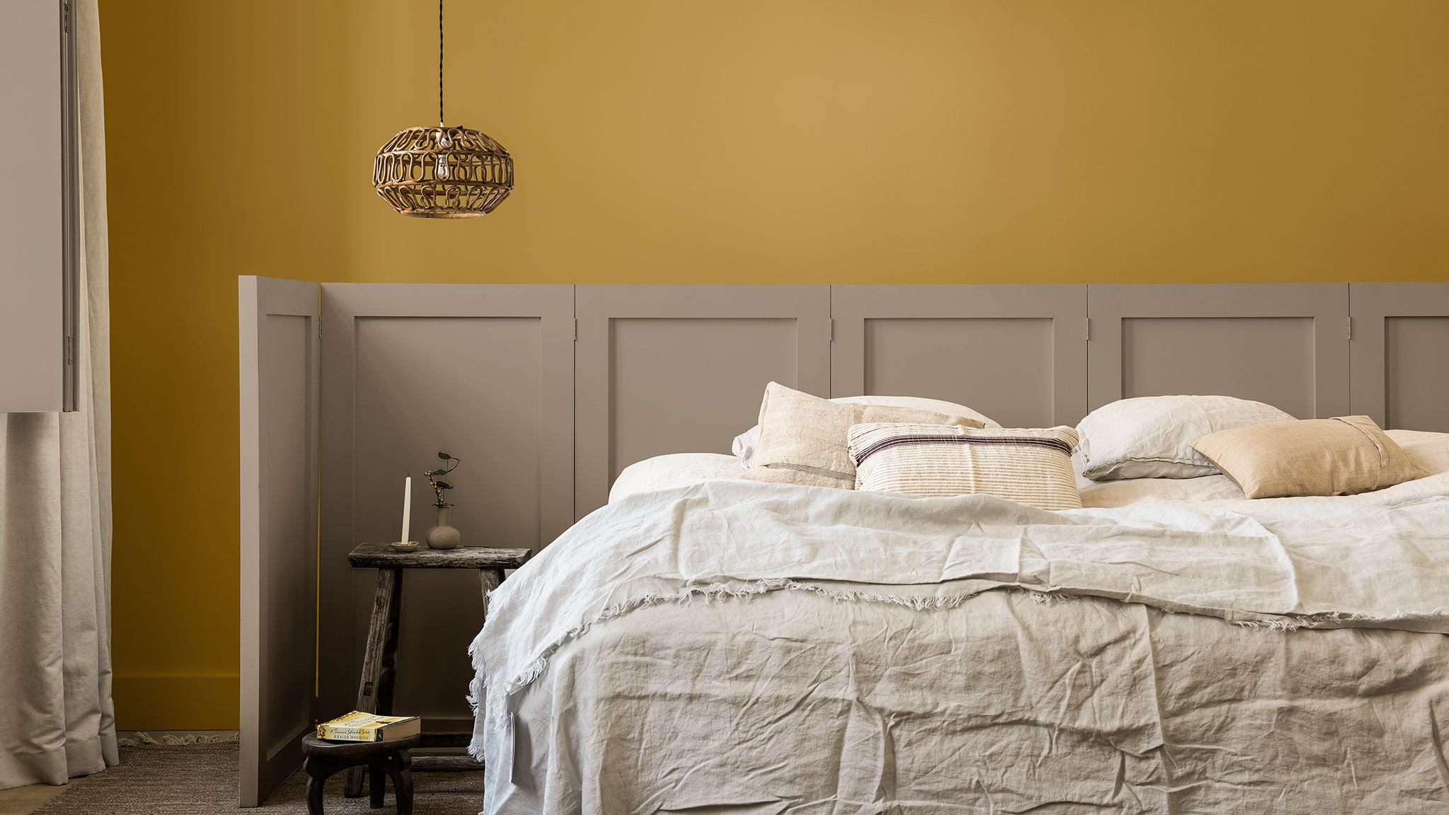 Pared del dormitorio en amarillo dorado y Brave Ground, con panel tras la cama Dulux_CF21_ Colour_of_the_year_Timeless_colors_global_2