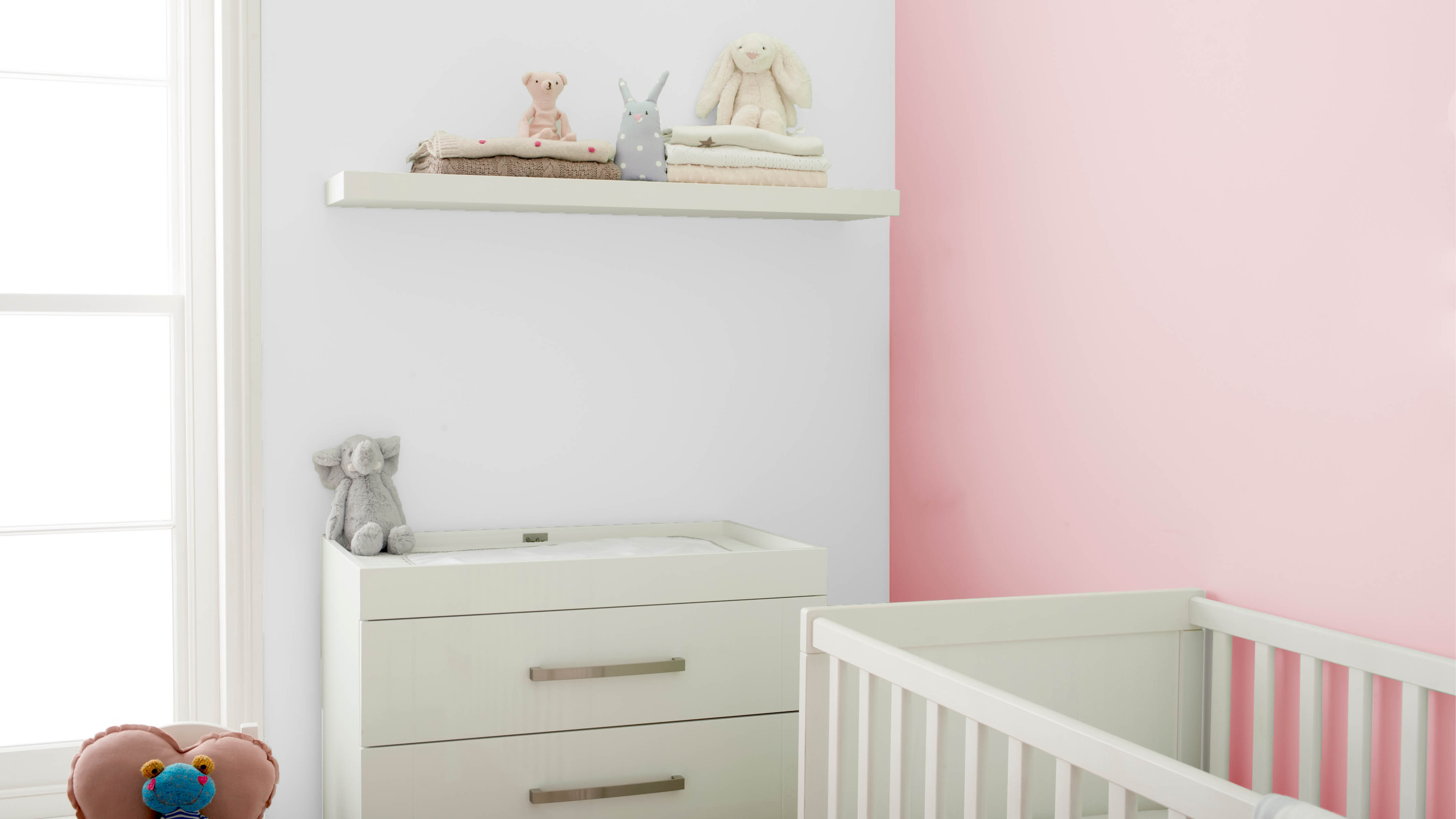 Habitación del bebé rosa con estanterías flotantes Un armario blanco y un conjunto de estanterías flotantes son un fantástico lugar para colocar peluches y otros objetos del bebé.